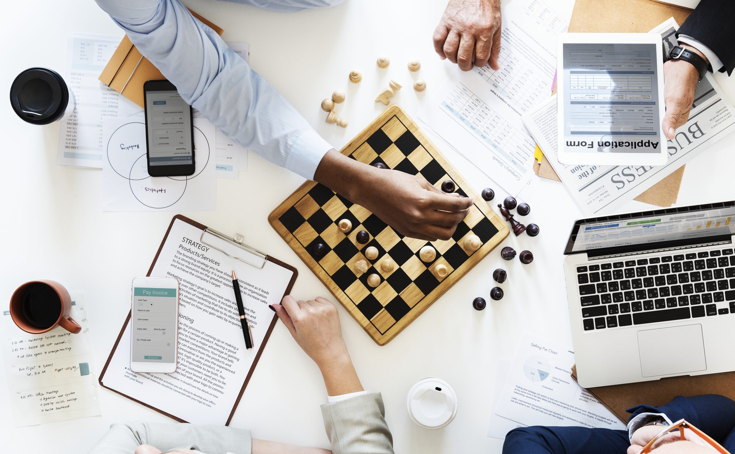 Business partners shaking hands over a strategic planning table